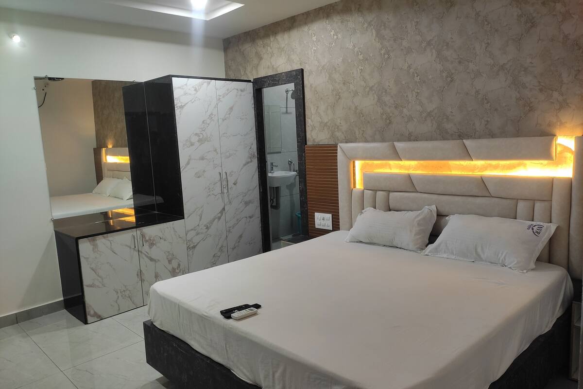 Un dormitorio moderno con una cama grande, una mesita de noche, un espejo y un armario empotrado.