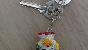 A keychain with a decorative figure and a key. - Sicilia Bedda Vacation Rental (Lascari)