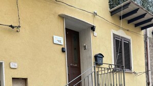 A stone staircase leading to a yellow building with a door and window. - Sicilia Bedda Vacation Rental (Lascari)