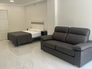 A modern hotel room with a bed, a sofa, and a nightstand. - Villa Amir (Fuengirola)