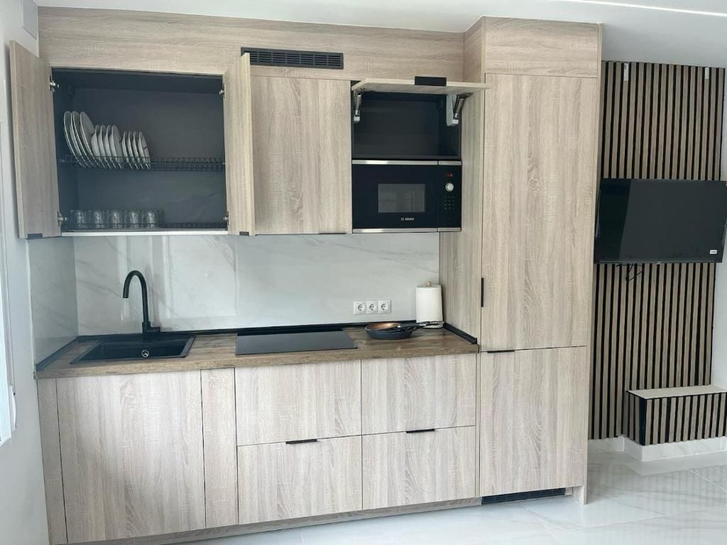 Eine moderne Küche mit Holzausstattung, einer eingebauten Mikrowelle und einem Spülbecken.