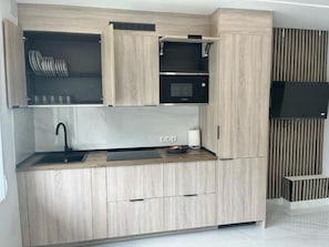 A modern kitchen with wooden cabinets, a built-in microwave, and a sink.