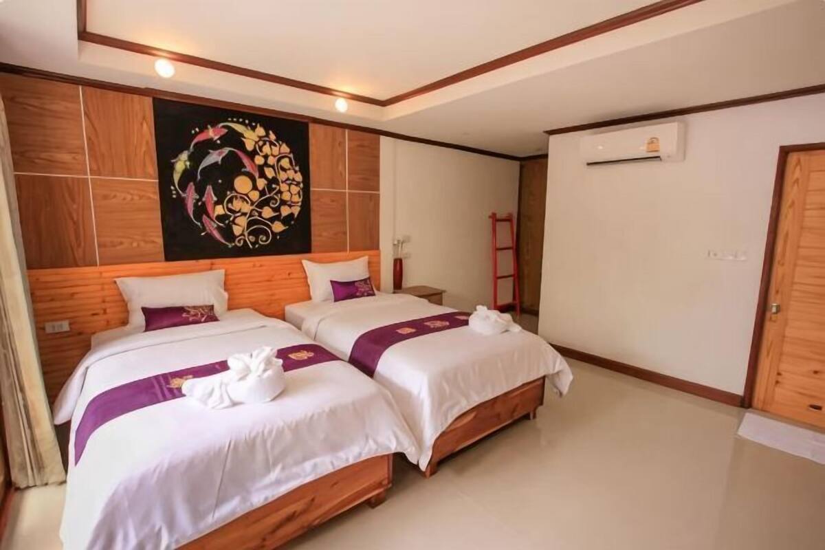 A hotel room with two beds, a wooden headboard, a wall-mounted air conditioner, and a red ladder.
