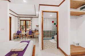 A hotel room with a bed, a desk, and a chair. There is a bathroom with a shower and a toilet. - The Villager Fishermans Village (Koh Samui)