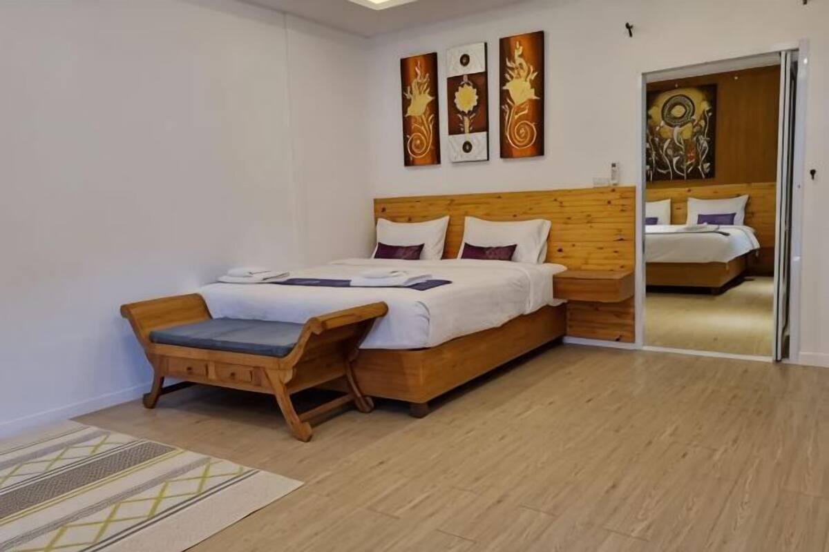 A bedroom with a wooden bed, a wooden nightstand, and a bench.