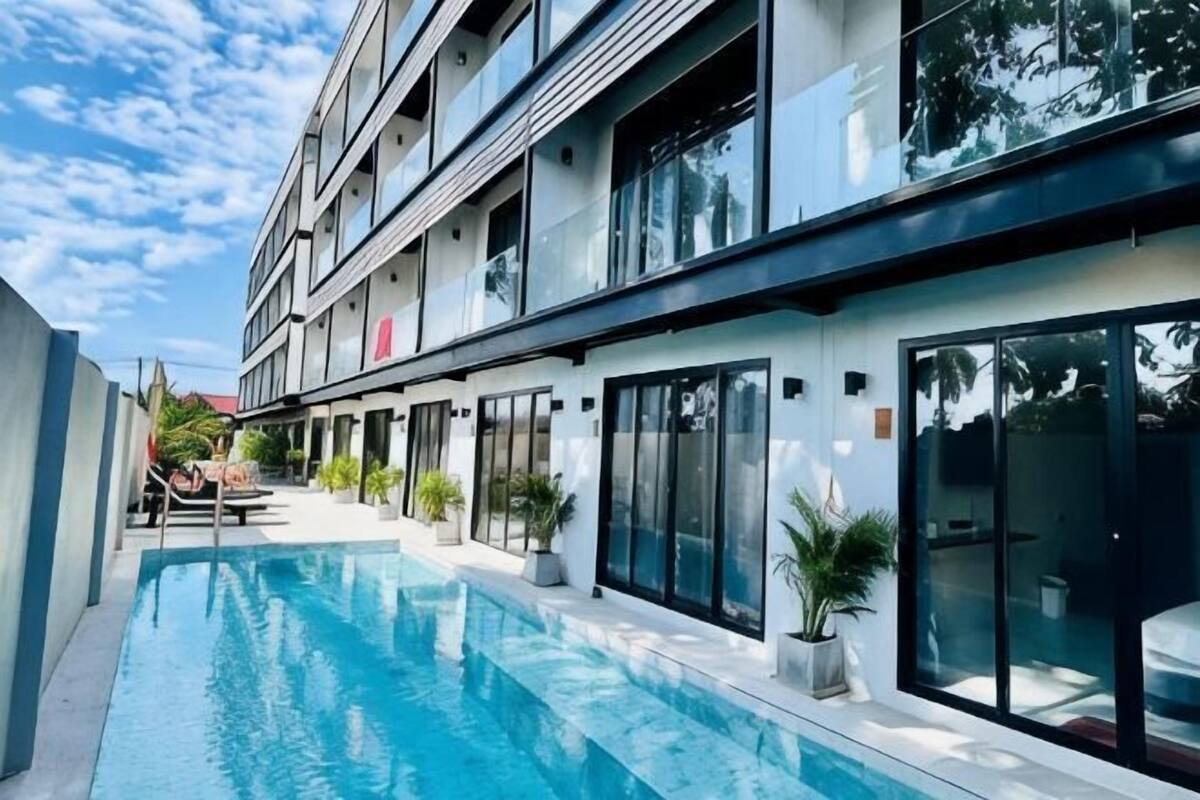A modern hotel with a swimming pool, large windows, and a multi-story structure.