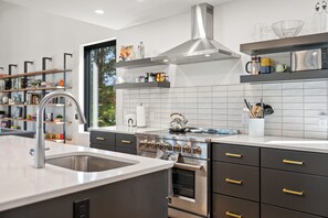 A modern kitchen with stainless steel appliances, a large window, and a built-in oven.