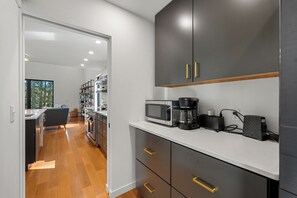 A modern kitchen with a microwave, coffee maker, and a power strip on the counter. - Modern Lakehouse on Quiet Peninsula (Lakeville)