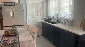Una cucina con tavolo, sedie, frigorifero, lavello e pensili.