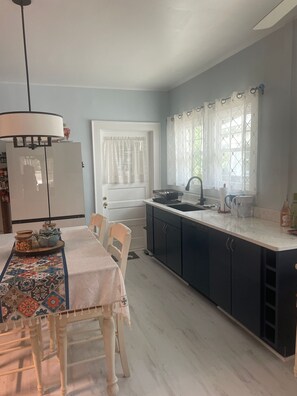 A kitchen with a dining table, chairs, a refrigerator, a sink, and cabinets. - Charming historic home close to the World Cup (Atlanta)