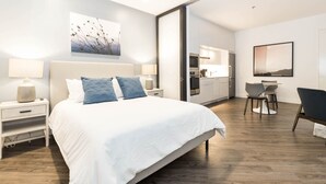 A modern hotel room with a large bed, a desk, and a kitchenette. - Landing Apartments New York  (Raritan)