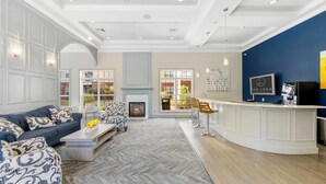 A modern living room with a sofa, coffee table, and a reception desk. - Landing Apartments New York  (Raritan)