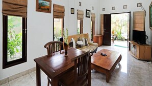 A room with a wooden dining table, chairs, a sofa, a television, and framed pictures on the walls. - Rumah Akira Seminyak (Bali)