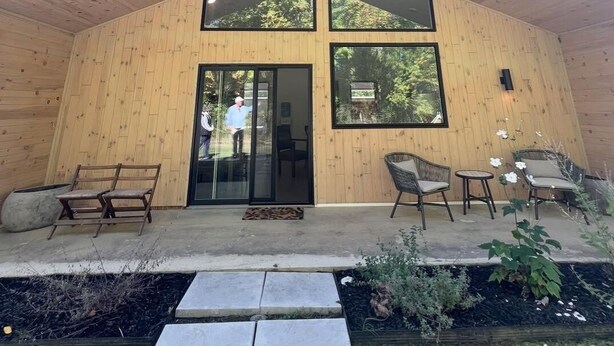 A modern wooden house with a sloped roof, large windows, and a patio with outdoor furniture. - The Cork Cottages, Unit 1, Arcade Table, Modern and New 2b/2b (Geneva)