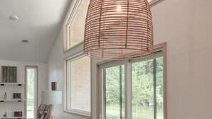 A modern dining area with a wooden table, chairs, and a unique woven pendant light. - The Cork Cottages, Unit 1, Arcade Table, Modern and New 2b/2b (Geneva)