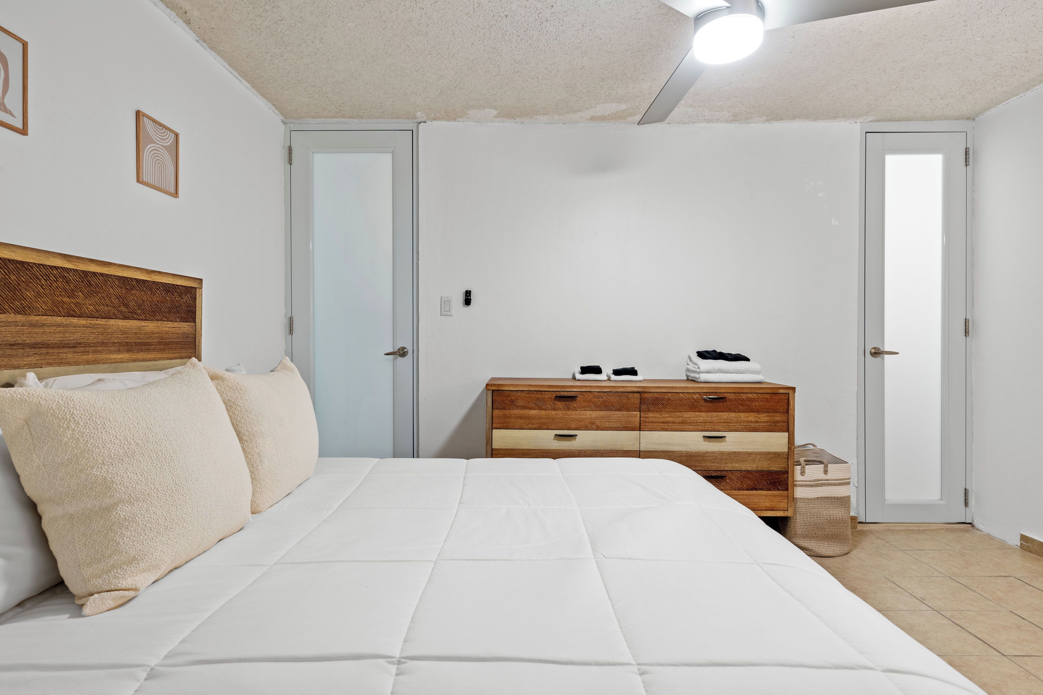 Een slaapkamer met een bed, een houten dressoir en een deur.