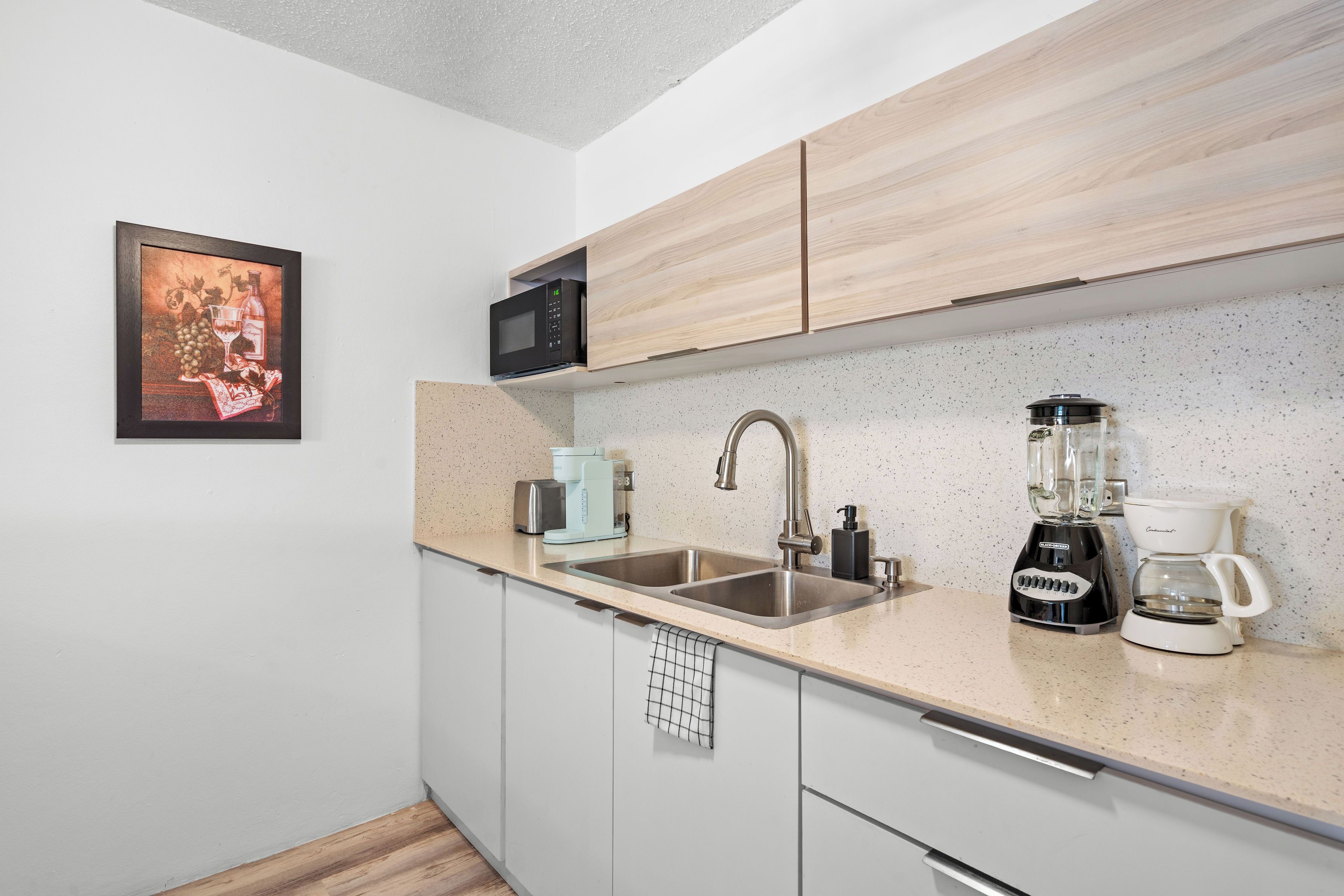A modern kitchen with a stainless steel sink, a coffee maker, and a microwave.