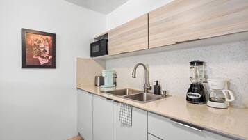 A modern kitchen with a stainless steel sink, a coffee maker, and a microwave.