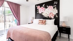 Ein Schlafzimmer mit einem Bett, zwei Nachttischen, einem Deckenventilator und einem großen Blumenbild an der Wand.