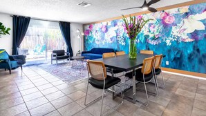 Ein modernes Wohnzimmer mit Essbereich, Deckenventilator und einer großen Blumenmalerei an der Wand.