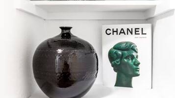 Un jarrón negro sobre una estantería con un libro titulado 'CHANEL' a su lado.
