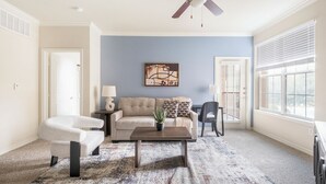 Ein Wohnzimmer mit einem beigen Sofa, einem Couchtisch, einem weißen Sessel und einer blauen Wand als Blickfang.