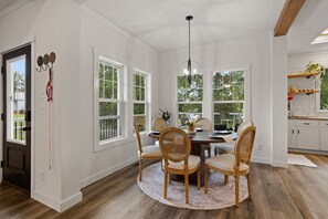 Un coin repas avec une table ronde, quatre chaises et un lustre.