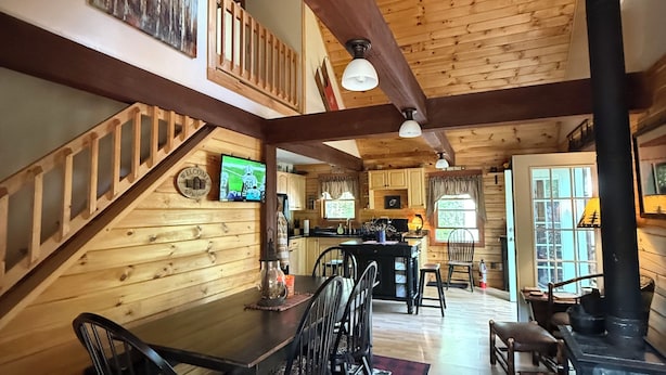 Un interior de madera con comedor, cocina y chimenea.
