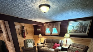 Una sala de estar acogedora con chimenea, paredes de madera y un techo con diseños intrincados.