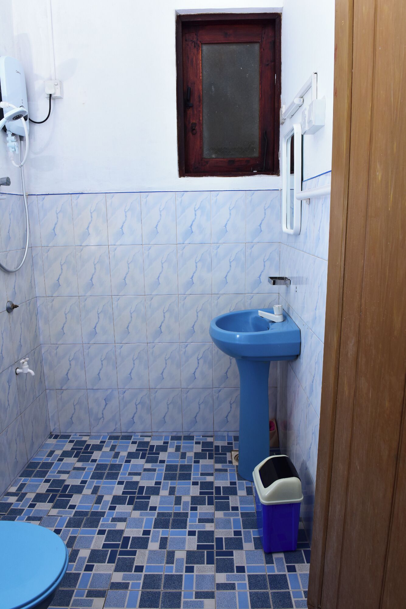 A small bathroom with a blue sink, a toilet, and a shower.