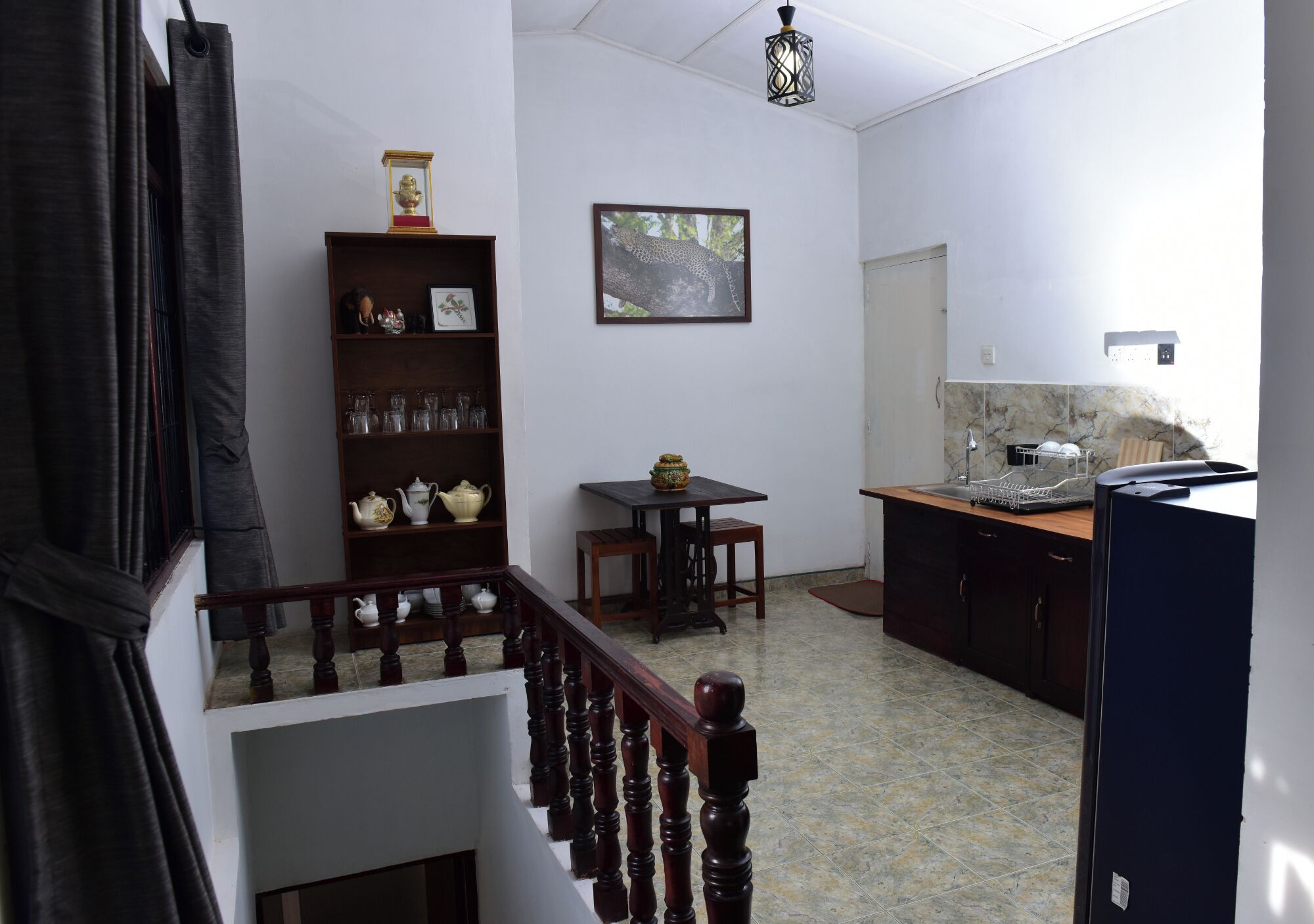 Una cucina con un tavolo da pranzo, uno scaffale pieno di utensili e un rivestimento in marmo.