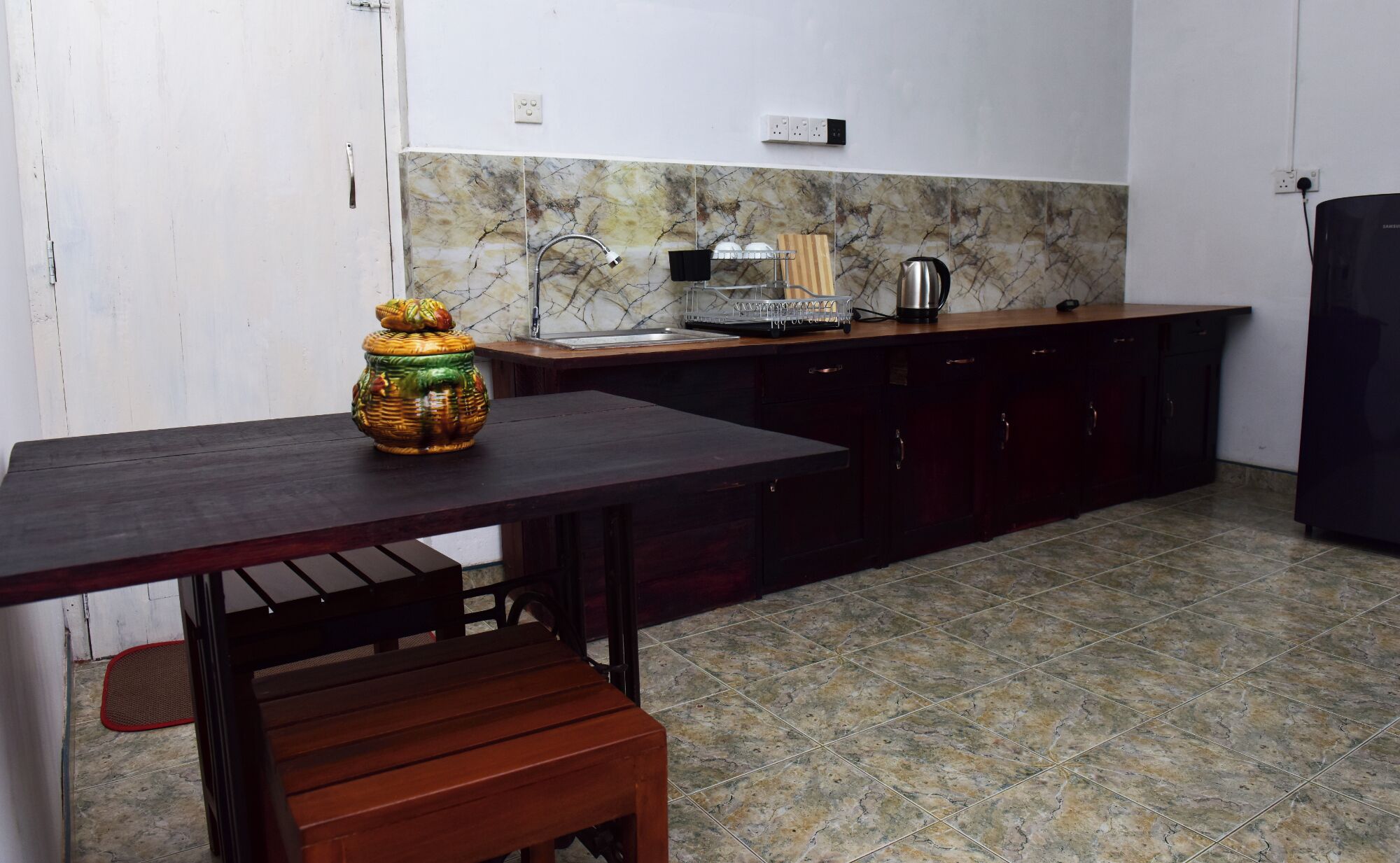Una cocina con salpicadero de mármol, una mesa de madera y encimera negra.
