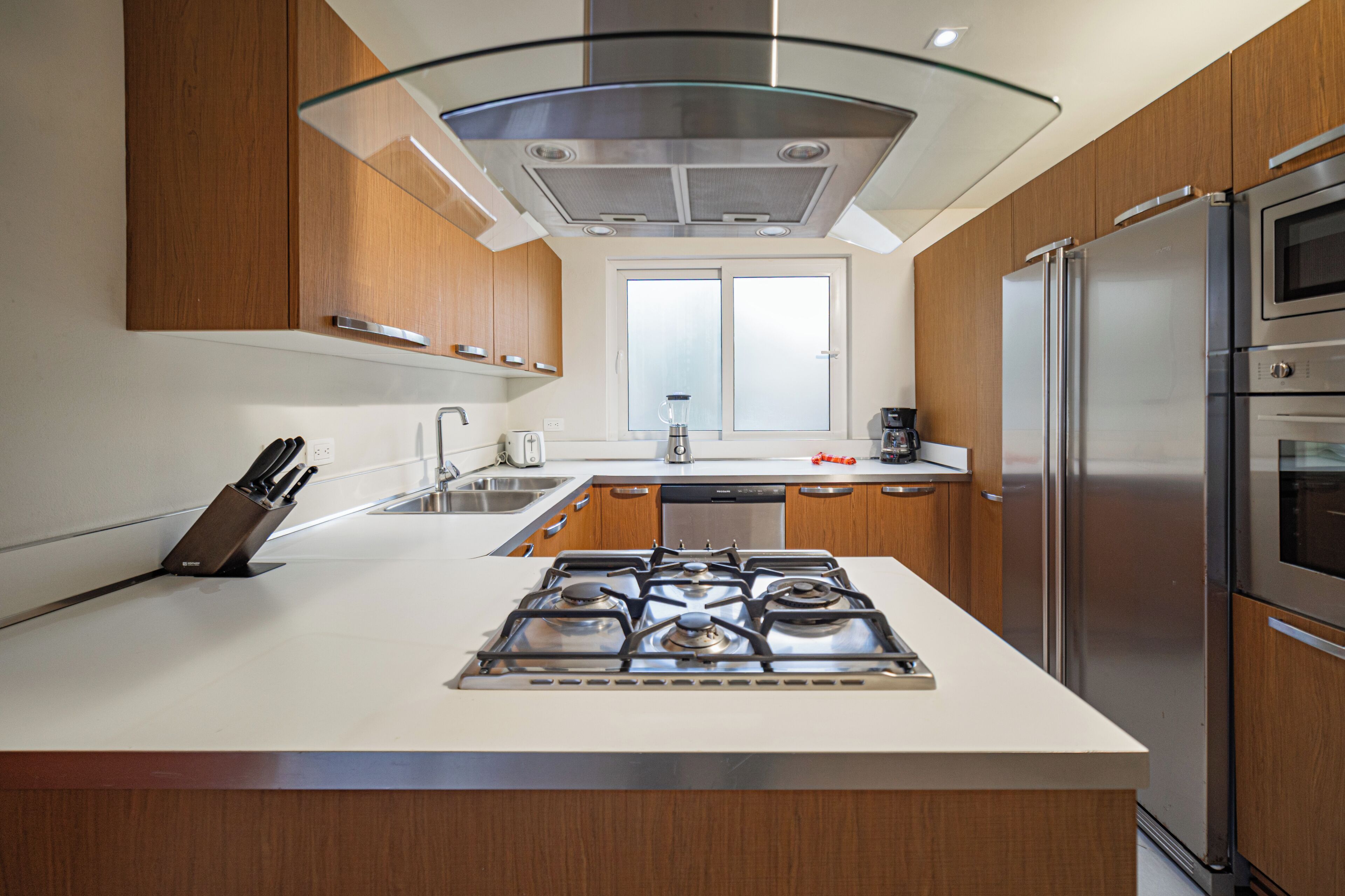A modern kitchen with a central island, stainless steel appliances, and wooden cabinets.