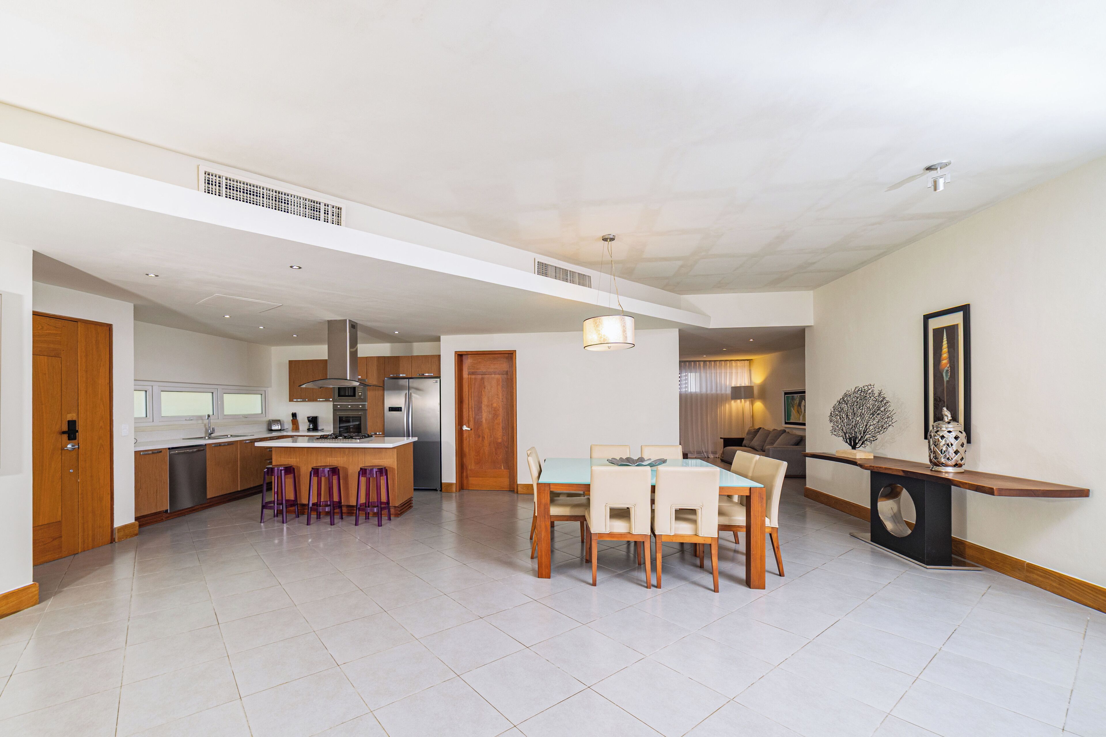 A spacious living area with a kitchen, dining table, and bar seating.