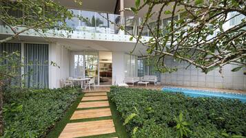 A modern building with a glass balcony, a pool, and a wooden pathway.