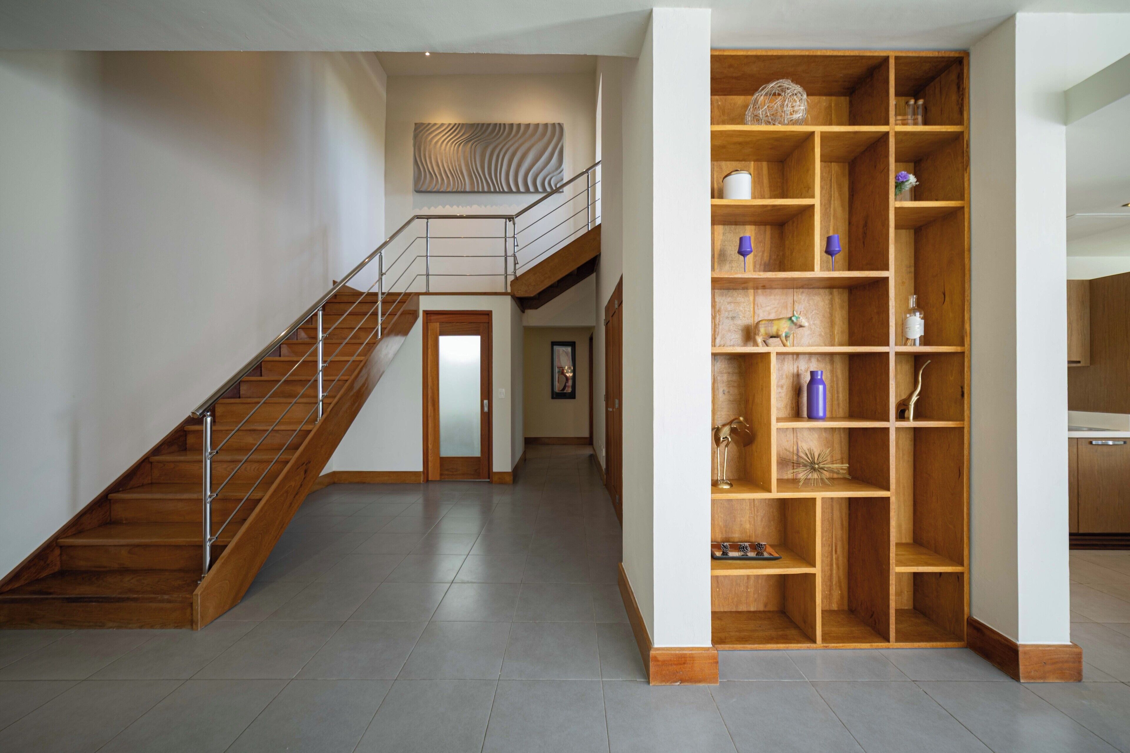 A spacious interior with a wooden staircase, a built-in wooden shelving unit, and a framed picture on the wall.