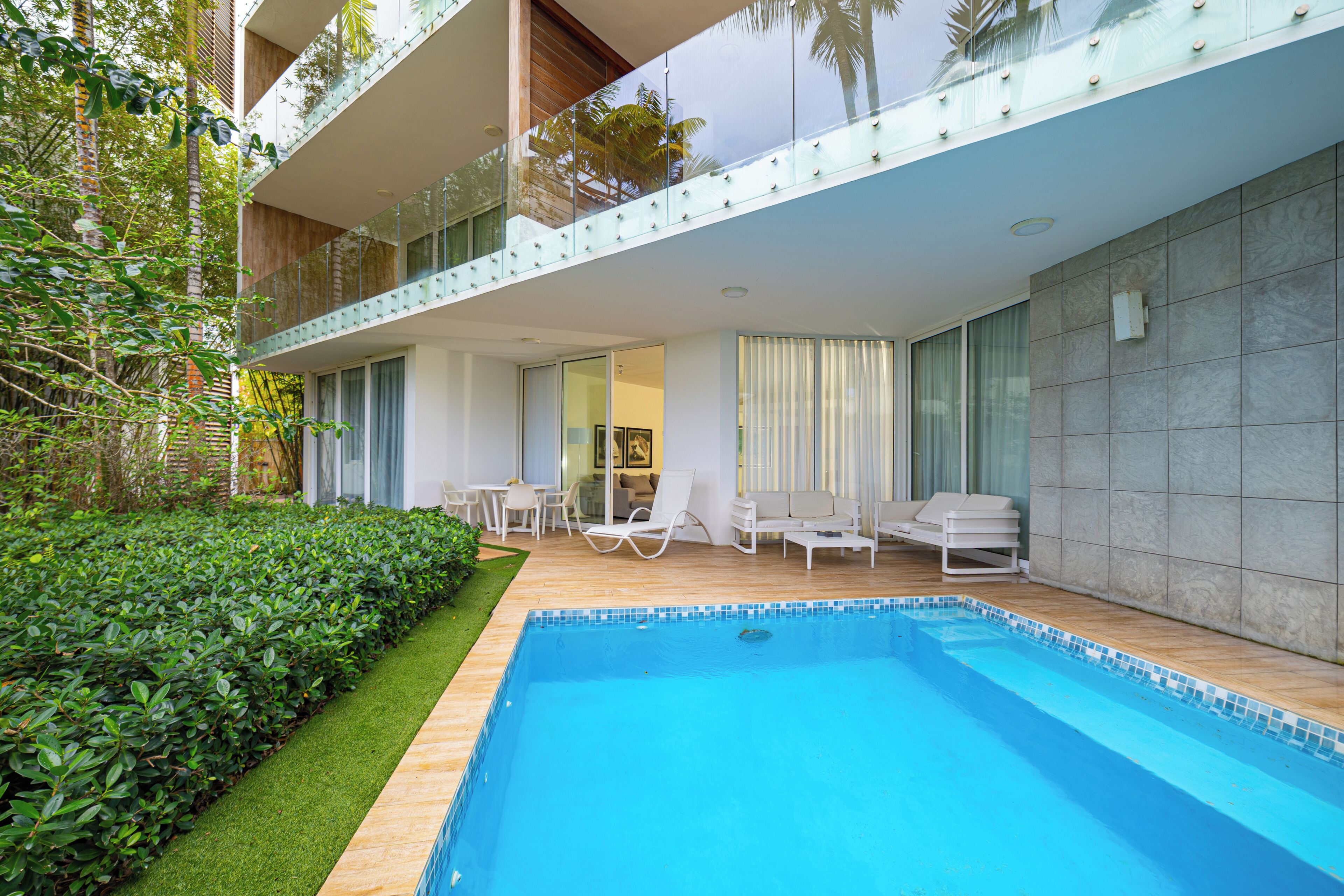Un hôtel moderne doté d’une piscine, d’un espace extérieur aménagé et d’une végétation luxuriante.