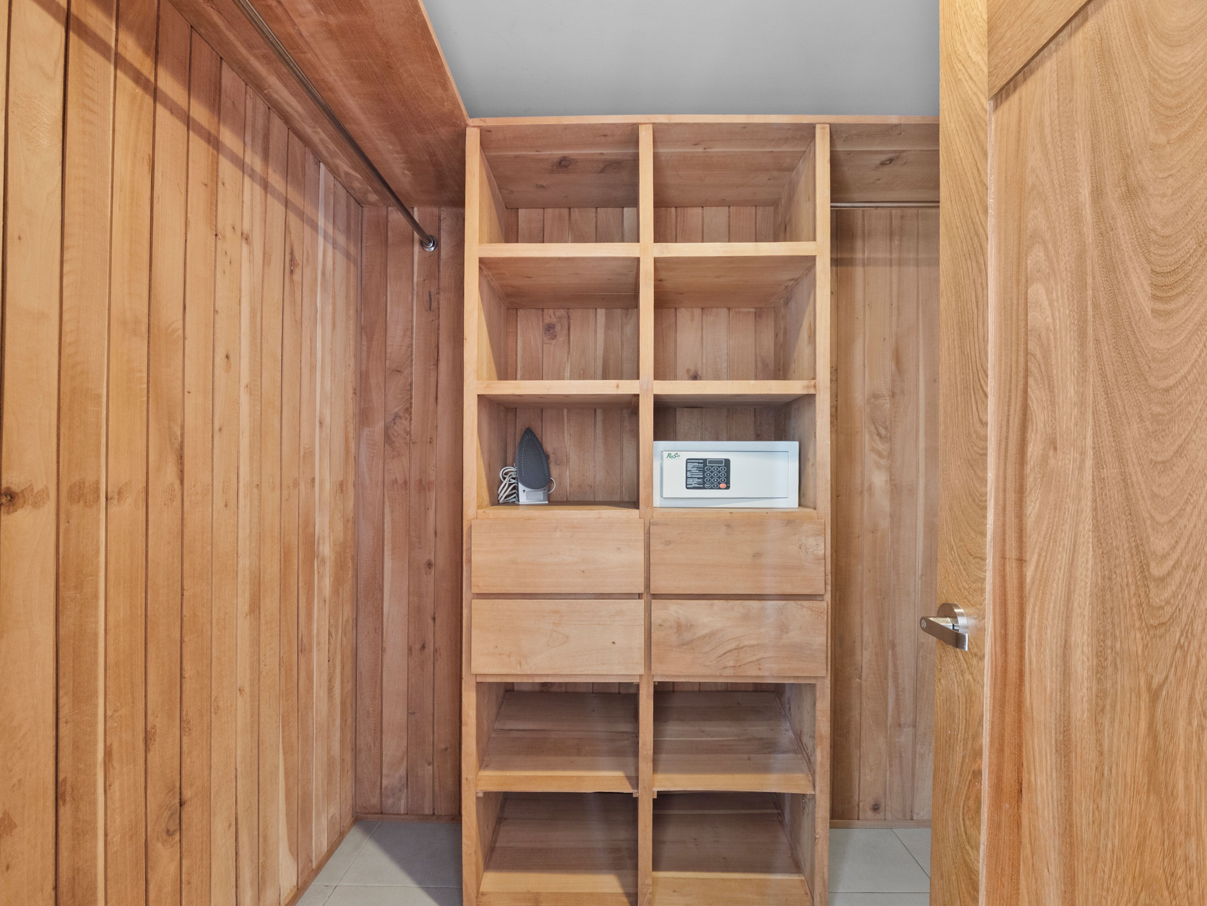 A wooden closet with multiple shelves and a small appliance.