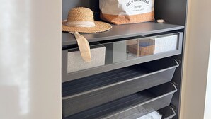 Un espace de rangement doté d’étagères, d’une tringle et d’un sac de rangement blanc sur lequel est inscrit « GET IT ORGANIZED Storage ».