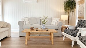 A living room with a striped sofa, a wooden coffee table, and a patterned armchair. - The Cottage (Brevard County)