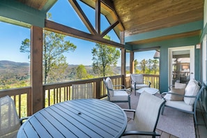 A covered outdoor seating area with a table and chairs, overlooking a mountainous landscape. - Wintergreens R331- Mtn Condo/View, Gated Resort, Indoor/Outdoor Pools & Hot Tub (Boone)