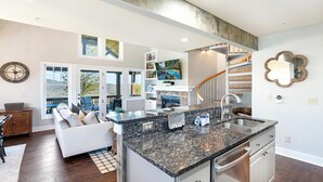 Une cuisine moderne dotée de plans de travail en granit, d’un lave-vaisselle intégré et d’un grand îlot central.