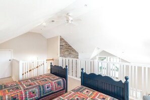 A bedroom with two beds, a sloped ceiling, a ceiling fan, and a stone accent wall. - Echota Wintergreens 1632- Mtn Condo, Gated Resort, Indoor/Outdoor Pools & Hot Tu (Boone)