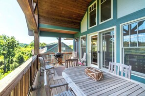 Una terraza techada con mobiliario de madera, una parrilla y una mesa con un pastel.