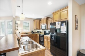 A modern kitchen with wooden cabinets, stainless steel appliances, and a large refrigerator. - Echota Wintergreens 1632- Mtn Condo, Gated Resort, Indoor/Outdoor Pools & Hot Tu (Boone)