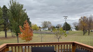 Eine Holzterrasse mit Korbmöbeln und Blick auf einen Park.