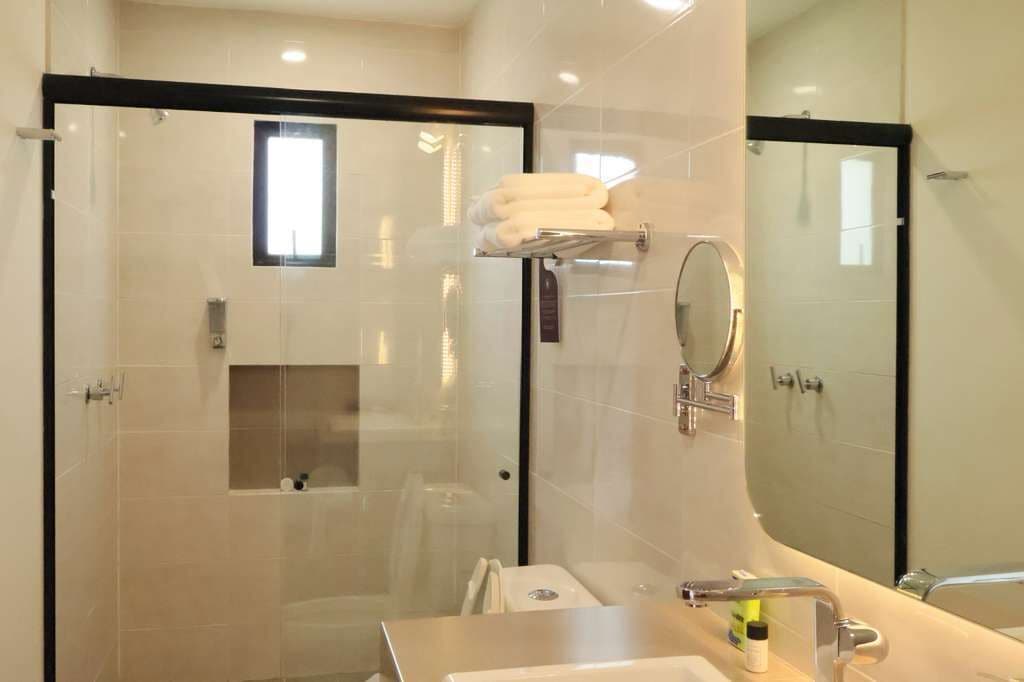 Un baño moderno con ducha envuelta en vidrio, tocador con lavabo y espejo.