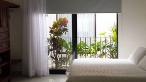 Ein Schlafzimmer mit Bett, einem Fenster mit Blick auf Grünflächen und einem Vorhang.