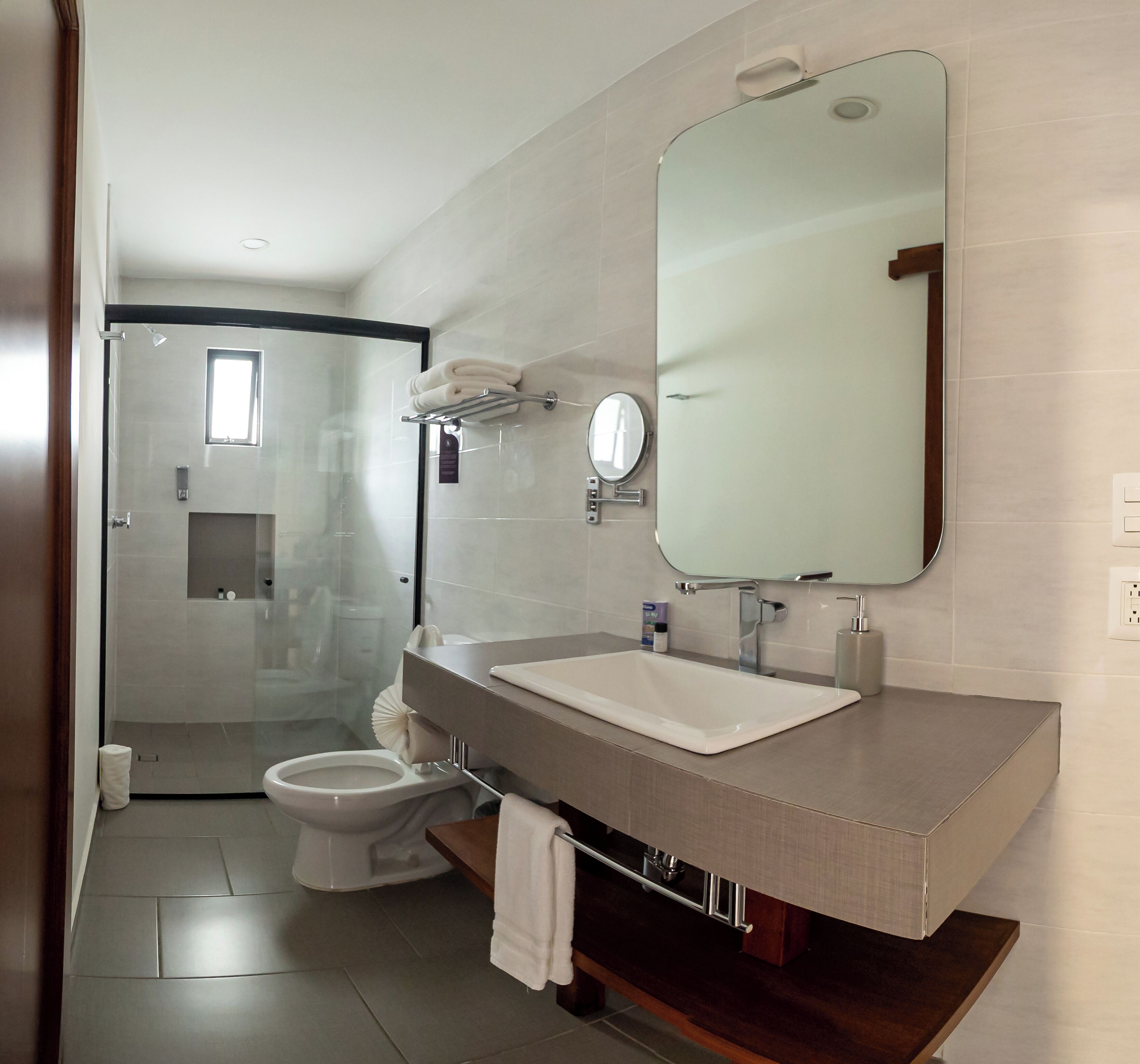 A modern bathroom with a large mirror, a sink, and a toilet.