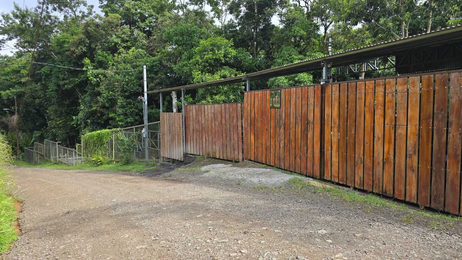 A gravel path leading to a wooden fence with a metal gate.